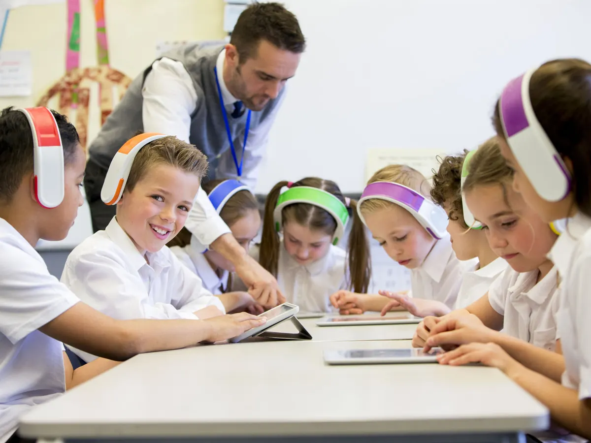 Alumnos de primaria usando tabletas en el salón con su maestro